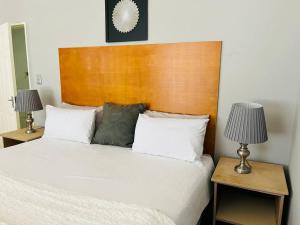 1 dormitorio con 1 cama blanca y 2 mesitas de noche en Private room in Rustenburg, en Rustenburg