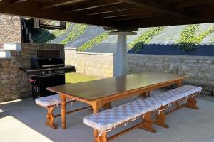 een houten tafel en bank met een grill en een picknicktafel bij La Casa del Marinero in Cudillero