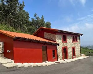 een rood en stenen gebouw met een rode deur bij La Casa del Marinero in Cudillero