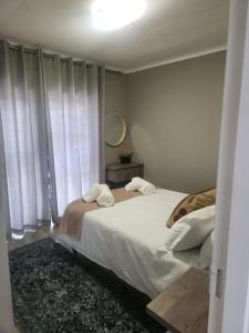 een slaapkamer met een bed met witte lakens en een spiegel bij The Galton Villa in Windhoek