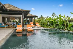 une piscine avec des chaises oranges et une maison dans l'établissement Kukui'ula Luxury Vacation Home 62- Alekona Kauai, à Koloa