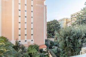 un immeuble d'appartements avec un jardin devant dans l'établissement Menton Casino, à Menton