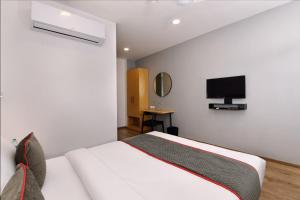 a bedroom with a white bed and a flat screen tv at Townhouse Function Inn Near Chaudhary Charan Singh International Airport in Charbagh