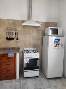 La cuisine est équipée d'une cuisinière blanche et d'un réfrigérateur. dans l'établissement Departamento Costanera Alta Gracia, à Alta Gracia