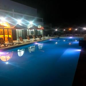 basen w nocy z krzesłami i światłami w obiekcie Hôtel Calipau Riad Maison d'Hôtes w mieście Dakhla