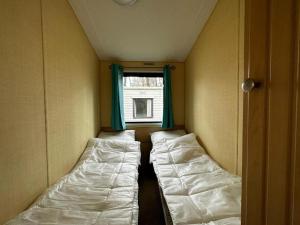 2 Betten in einem kleinen Zimmer mit Fenster in der Unterkunft Goolderheide 369 in Bocholt