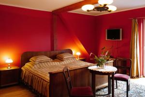 een slaapkamer met een bed met rode muren en een tafel bij Dworek Drawa in Drezdenko