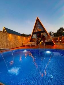 a swimming pool with a pyramid shaped house behind it at Joy Sapanca in Sapanca