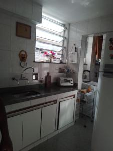 Elle comprend une petite cuisine avec un évier et une fenêtre. dans l'établissement Apartamento aconchegante, à Rio de Janeiro