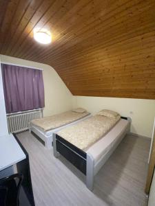 two beds in a room with a wooden ceiling at Niederdorf, Baselland Hotel in Niederdorf