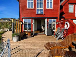 Casa roja con terraza de madera con sillas en Sea, Jacuzzi, Beach, Seaview, Boat, en Forland