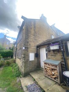 une maison en briques avec un banc devant elle dans l'établissement The Weavers Cottage, à Oxenhope