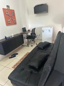 a living room with a black leather couch and a desk at Flat com Ar Condicionado Ana Regis AP 307, Salvador in Salvador
