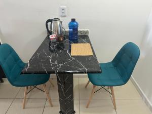 einen Tisch mit zwei blauen Stühlen und einer schwarzen Arbeitsplatte in der Unterkunft Flat com Ar Condicionado Ana Regis AP 307, Salvador in Salvador