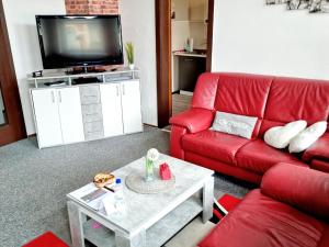 a living room with a red couch and a tv at Ferienwohnung "Blick Mylau" - Nähe Freizeitpark Plohn & weltgrößter Ziegelsteinbrücke in Reichenbach im Vogtland