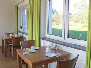 a dining room with a wooden table and windows at Gästehaus am Reisberg in Gaimersheim