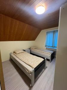 two beds in a room with a wooden ceiling at Niederdorf, Baselland Hotel in Niederdorf