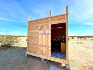 a wooden out house in the middle of the desert at Beysicair Tents & Campground in California City