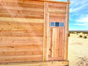 a wooden outhouse in the middle of the desert at Beysicair Tents & Campground in California City