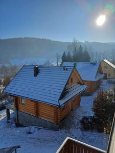 a log cabin with a blue roof in the snow at Domki po balu 