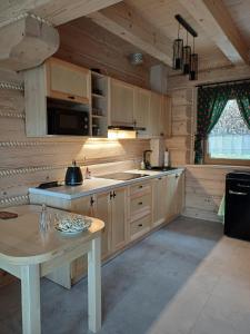 a large kitchen with wooden cabinets and a table at Domki po balu 