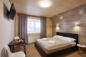 1 dormitorio con cama, mesa y TV en Woodvel House en Palyanytsya