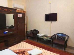 Habitación con TV, 2 sillas y mesa. en Furnish Rooms Near Jinnah Airport en Karachi