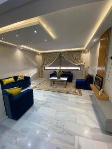 uma sala de estar com sofás azuis e uma mesa em Appartement neuf et élégant em Fez