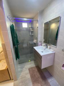 uma casa de banho com um lavatório e um chuveiro com um espelho. em Appartement neuf et élégant em Fez