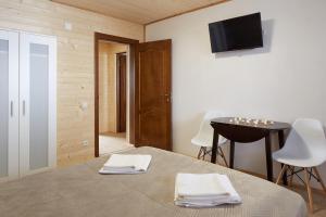 1 dormitorio con 1 cama y 1 mesa con toallas blancas en Woodvel House en Palyanytsya