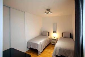 een slaapkamer met 2 bedden en een lamp op een houten vloer bij Appartement neuf 3 ch équipé in Thiais