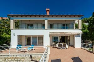 a large white house with a patio with blue chairs at Villa K Dubrovnik-5 bedroom villa with sea access in Zaton