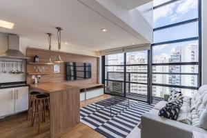 a kitchen and living room with a large window at Flat duplex com serviço de camareira e enxoval completo - ao lado do parque Ibirapuera in Sao Paulo