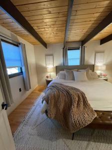 um quarto com uma cama grande e 2 janelas em Cozy Poconos retreat on Bushkill Creek w/ Firepit! em East Stroudsburg
