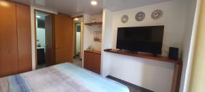 een slaapkamer met een flatscreen-tv aan de muur bij Bonito y cómodo apartamento cerca a Plaza Mayor in Medellín