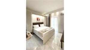 1 dormitorio con cama blanca y ventana en Myrto Rooms, en Pefkohori