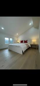 a white bedroom with a large bed with red pillows at 6 BEDROOM MODERN AND LUXURY HOME in Welland