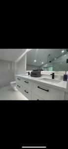 a white bathroom with a sink and a mirror at 6 BEDROOM MODERN AND LUXURY HOME in Welland