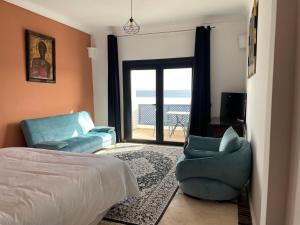 ein Schlafzimmer mit einem Bett und einem Stuhl sowie einem Balkon in der Unterkunft Hôtel Calipau Riad Maison d'Hôtes in Ad-Dakhla