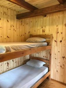 Ce lit se trouve dans un dortoir doté de 2 lits superposés et de murs en bois. dans l'établissement Chacra Celeste: montañas y mar, à Piriápolis