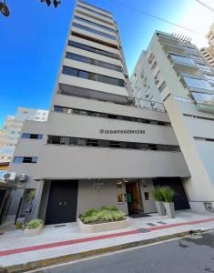 a tall white building with plants in front of it at Cobertura Baixa Coral Gables in Balneário Camboriú