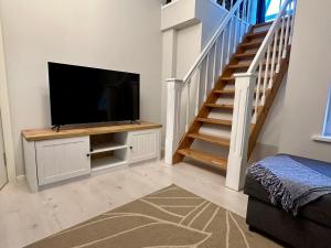 a living room with a flat screen tv and a staircase at Captain's House - Kaptenimaja - Apartments in Kärdla