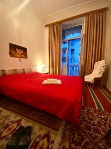 Habitación de hotel con cama roja y ventana en My Home Guest House en Bakú