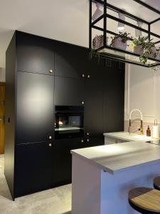 a kitchen with black cabinets and a white counter top at Malinowy Apartament in Zamość