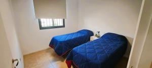 1 dormitorio con 2 camas azules y ventana en Balcones Mendocinos en Mendoza