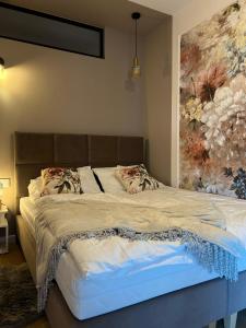 a bed in a bedroom with a painting on the wall at Malinowy Apartament in Zamość +40 photos