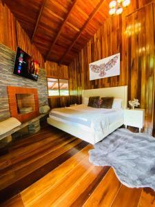 1 dormitorio con 1 cama y TV en la pared en The Wooden House Mindo, en Mindo