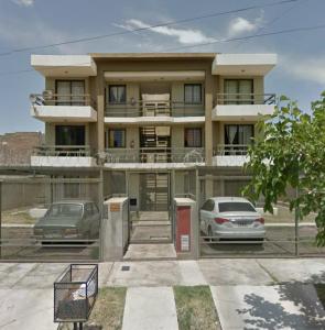 un edificio con dos coches estacionados frente a él en Balcones Mendocinos en Mendoza