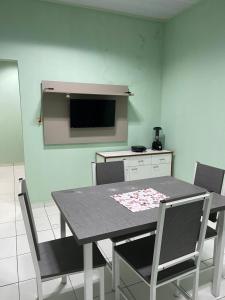 a dining room with a table and chairs and a tv at Kitnet na cidade nova in Ananindeua