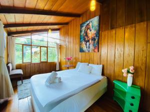 ein Schlafzimmer mit einem großen weißen Bett an einer Holzwand in der Unterkunft Wooden House Mindo - Casa de Las Nevadas in Mindo